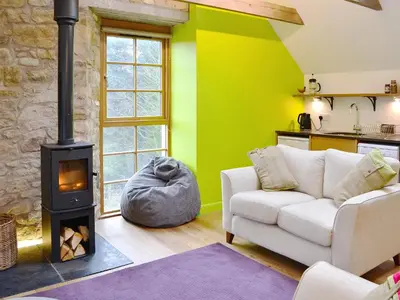 a living room with a couch and a stove at The Hayloft in Blitterlees