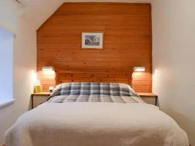 a bed in a room with a wooden wall at Craig Lora in Dalmally
