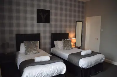 a hotel room with two beds and a mirror at Kelpies Serviced Apartments McDonald- 2 Bedrooms in Falkirk