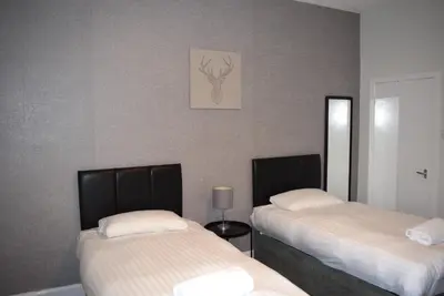 a room with two beds and a picture on the wall at Kelpies Serviced Apartments McDonald- 2 Bedrooms in Falkirk