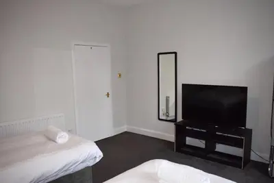 a bedroom with a flat screen tv and a mirror at Kelpies Serviced Apartments McDonald- 2 Bedrooms in Falkirk