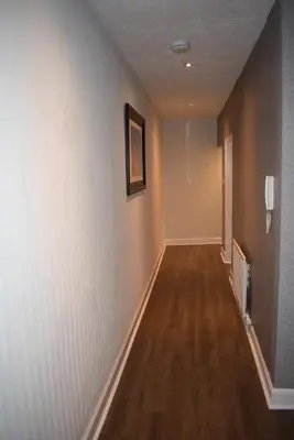 a hallway with white walls and a wooden floor at Kelpies Serviced Apartments McDonald- 2 Bedrooms in Falkirk