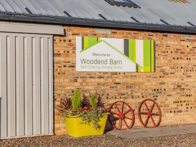 a sign on a brick building with two flower pots at Woodend Barn in Auchterarder