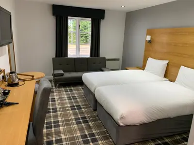 a hotel room with two beds and a couch at Crowwood Hotel and Alba Restaurant in Chryston