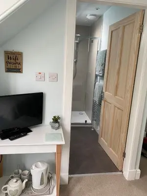 a bathroom with a walk in shower next to a door at Alpine cottage in Crieff