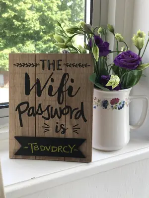 a sign on a window sill with a vase of flowers at Alpine cottage in Crieff