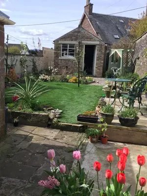 a garden with pink flowers and a house at Alpine cottage in Crieff