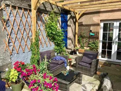 a pergola with chairs and flowers on a patio at Alpine cottage in Crieff