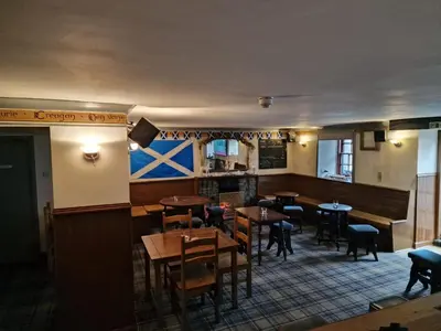 a restaurant with tables and chairs and a flag on the wall at The White Stag Inn in Strathyre