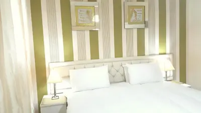 a bedroom with a white bed with green and white stripes at Loch Lomond Apartments in Dumbarton