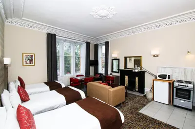 a hotel room with three beds and a fireplace at City Apartments in Glasgow