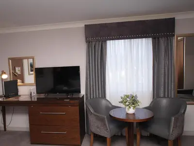 a hotel room with a desk and a television and chairs at Golden Lion Hotel in Stirling