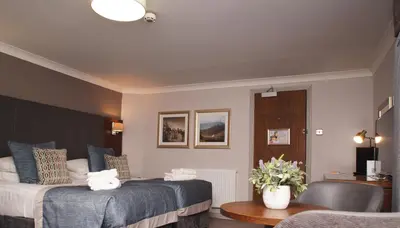 a hotel room with two beds and a table and a room at Golden Lion Hotel in Stirling