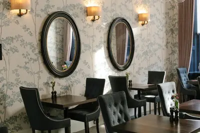 a restaurant with tables and mirrors on the wall at Nira Caledonia in Edinburgh