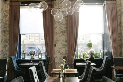 a dining room with tables and chairs and windows at Nira Caledonia in Edinburgh