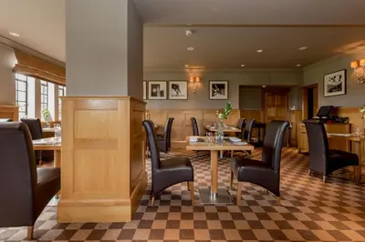 a dining room with a table and black chairs at Western House Hotel At Ayr Racecourse in Ayr