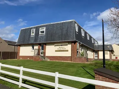 a house with a white fence in front of it at Western House Hotel At Ayr Racecourse in Ayr