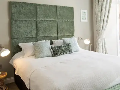 a bedroom with a large bed with a green headboard at The Lane Hotel in Edinburgh