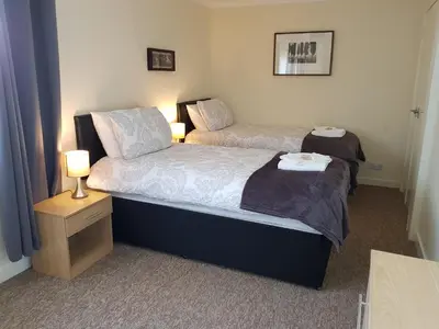 a bedroom with two beds and a night stand with a lamp at Workforce Property in Kirk of Shotts