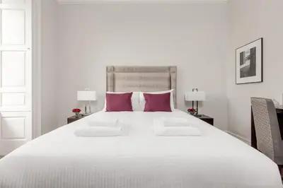 a large white bed with two pink pillows at Destiny Scotland - Chisholm Hunter Suites in Edinburgh