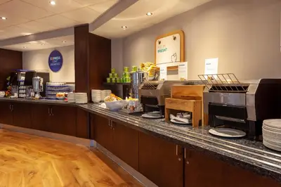 a restaurant with a counter with aasteryasteryasteryasteryasteryasteryasteryasteryastery at Holiday Inn Express - Glasgow - City Ctr Theatreland by IHG in Glasgow