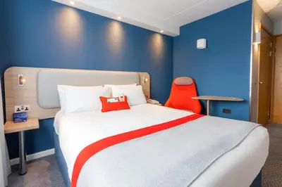 a hotel room with a large bed with a red chair at Holiday Inn Express - Glasgow - City Ctr Theatreland by IHG in Glasgow