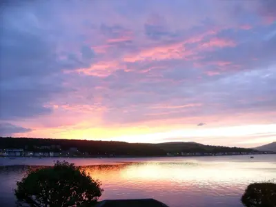 a sunset over a large body of water at Commodore Guesthouse, Seaside Holiday Suites in Rothesay