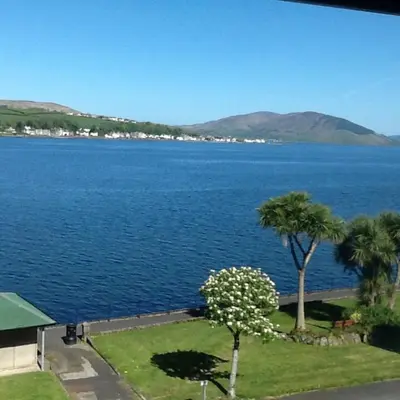 a view of a large body of water with palm trees at Commodore Guesthouse, Seaside Holiday Suites in Rothesay