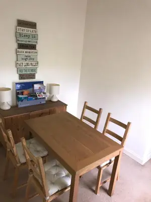a wooden table with two chairs and a table with a sign at Ayrshire cottage in Kilmarnock