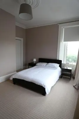 a bedroom with a large bed and a window at Ayrshire cottage in Kilmarnock