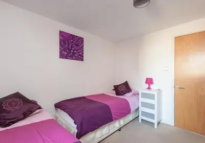 a bedroom with two beds and a wooden door at The Metropole Residence in Glasgow