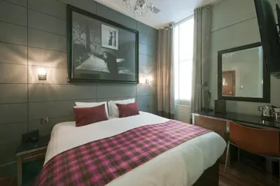 a bedroom with a large bed with red pillows at Angels Share Hotel in Edinburgh