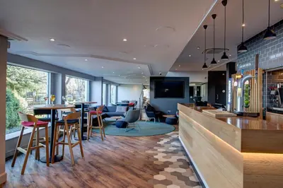 a restaurant with a bar with tables and chairs at Holiday Inn Express Edinburgh City West by IHG in Edinburgh