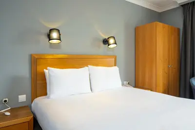 a bedroom with a white bed and a wooden headboard at Holiday Inn Edinburgh Zoo by IHG in Edinburgh