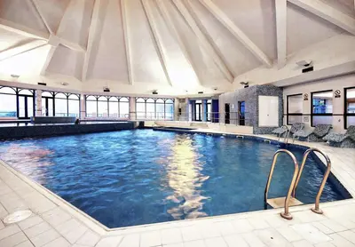 a large swimming pool in a building with windows at Glasgow Westerwood Hotel, Spa & Golf Resort in Cumbernauld