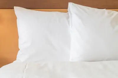 a bed with white sheets and pillows on it at Holiday Inn Express Dunfermline by IHG in Dunfermline