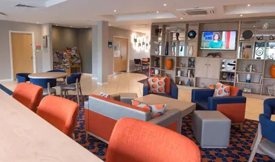 a waiting room with orange and blue chairs and tables at Holiday Inn Express Dunfermline by IHG in Dunfermline