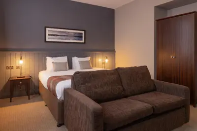 a hotel room with a bed and a couch at Rosslea Hall Hotel in Rhu
