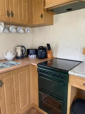 a kitchen with a black stove top oven next to a sink at Curacao Caravans in Taynuilt