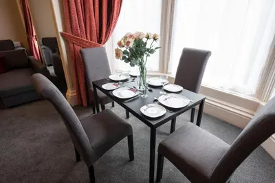 a table with chairs and a vase of flowers on it at Grosvenor Suites in Edinburgh