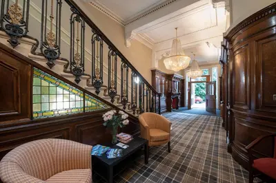 a hallway with a staircase with chairs and a table at Grosvenor Suites in Edinburgh