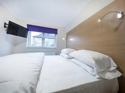 a bedroom with a bed with white sheets and a window at The Bay Horse in Hamilton