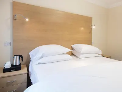a bedroom with two white beds and a wooden headboard at The Bay Horse in Hamilton