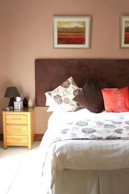 a bedroom with a large bed with a wooden headboard at Backbrae House B&B in Lanark