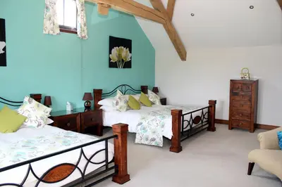a bedroom with two beds and a chair in it at Backbrae House B&B in Lanark