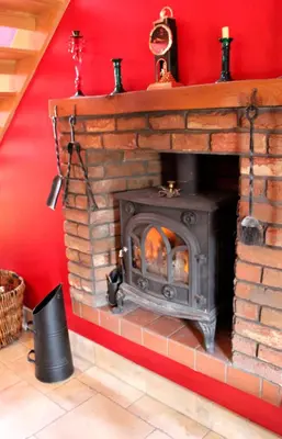 a brick fireplace in a red room with a stove at Backbrae House B&B in Lanark
