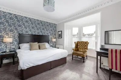 a bedroom with a bed and a tv and a chair at Kirkstyle Hotel in Biggar