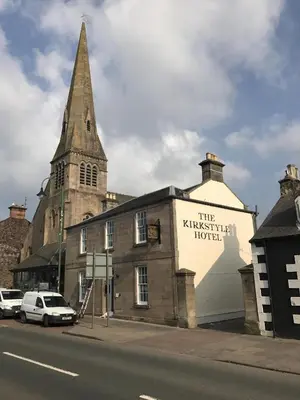 a sign on the side of a building with a church at Kirkstyle Hotel in Biggar