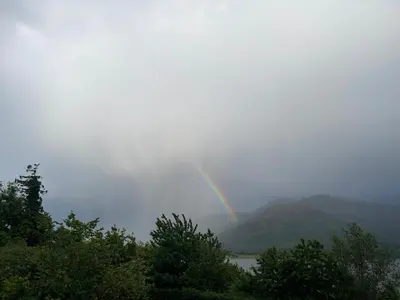 a rainbow in the sky over a river with trees at Creag Mhor Lodge in Onich