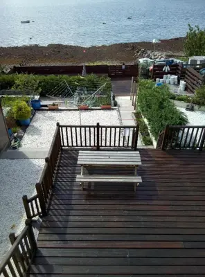 a wooden deck with benches and the ocean in the background at Maggie's in Inveraray